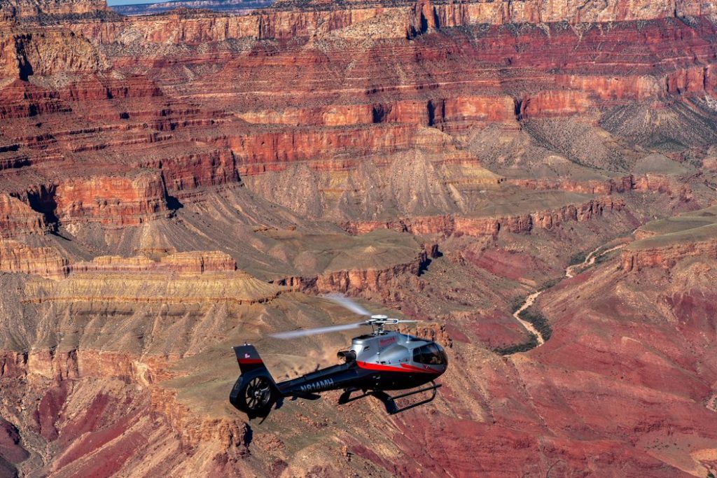 Sightseeing helicopter flying past red rock canyon formations