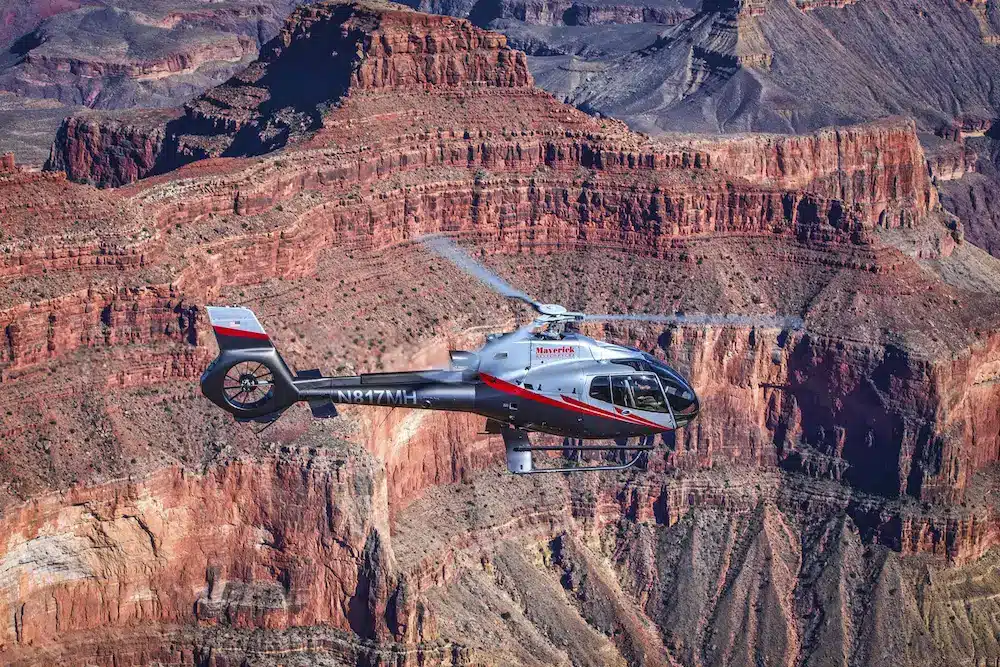 West Rim vs South Rim image Helicopter flying over the layered red walls of the Grand Canyon